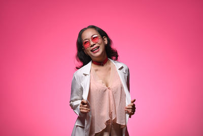 Portrait of young woman standing against yellow background