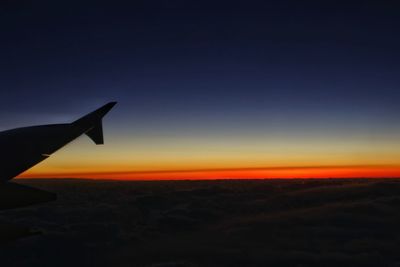 Close-up of airplane wing against sky during sunset