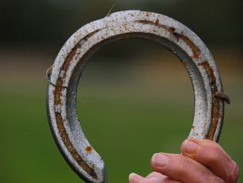 Close-up of hand holding rusty metal horseshoe