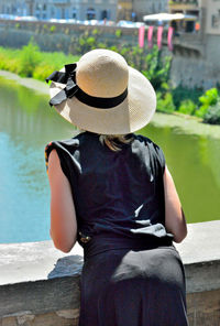 Rear view of woman sitting by lake