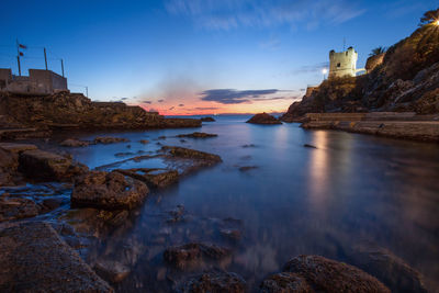 Scenic view of sea by buildings against sky during sunset