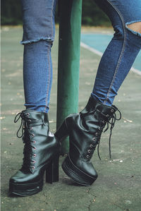 Low section of woman wearing black boots on footpath