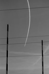 Low angle view of cables with vapor trail against sky