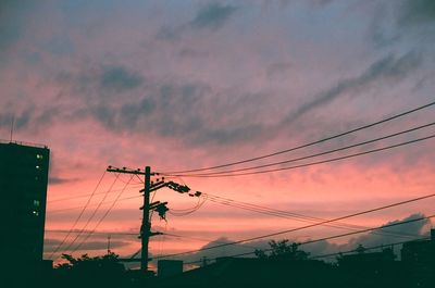 Low angle view of electricity pylon against cloudy sky