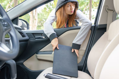 Woman holding laptop in car