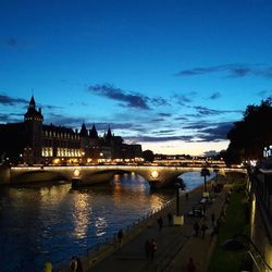 Illuminated bridge over river against blue sky at night