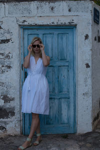 Full length portrait of woman standing by door