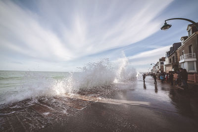 Waves splashing on street against sky