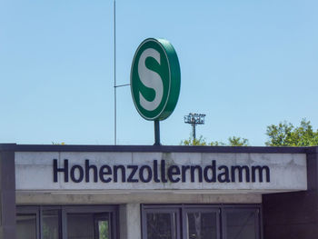 Low angle view of road sign against clear blue sky