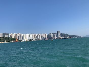 Scenic view of sea and buildings against clear blue sky
