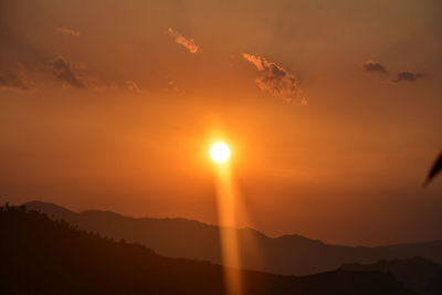 Scenic view of silhouette mountains against orange sky