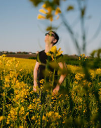 Young woman standing amidst yellow flowering plants on field