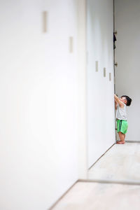 Rear view of woman standing against white wall