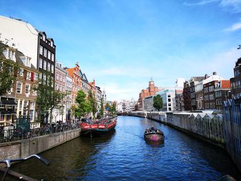 Canal amidst buildings in city against sky