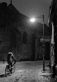 Man cycling on illuminated street at night