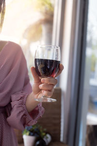 Midsection of woman holding glass