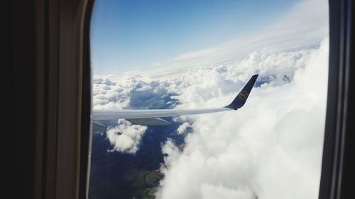 Airplane flying against sky seen through glass window