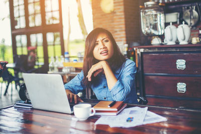 Young woman using phone while sitting on table