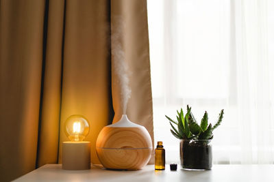 Aromatherapy concept. aroma oil diffuser on the table against the window.