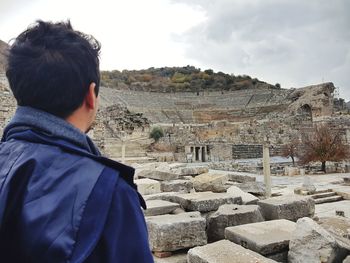 Rear view of man standing against old ruins