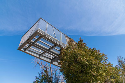 Low angle view of trees and building against blue sky