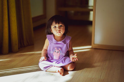 Portrait of cute boy sitting on floor at home