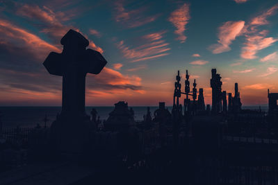 Silhouette statue in a graveyard  against sky during sunset