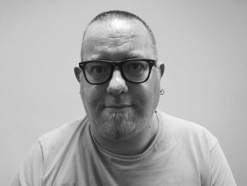 Portrait of man wearing eyeglasses against gray background