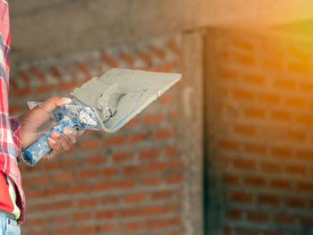 Man holding umbrella against wall