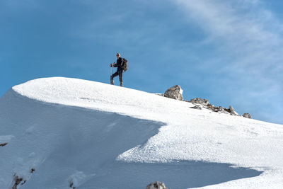 Man skiing on snowcapped mountain against sky