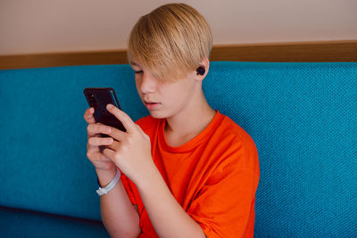 Young boy using mobile phone while sitting on sofa at home