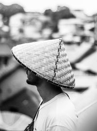 Side view of man wearing asian style conical hat while standing outdoors