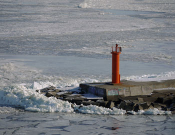 Lighthouse by sea against buildings