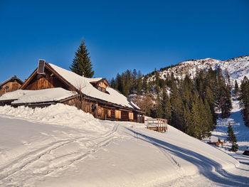 Houses on snow covered landscape against clear blue sky