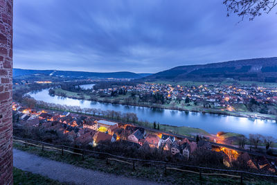 High angle view of illuminated city by river against sky