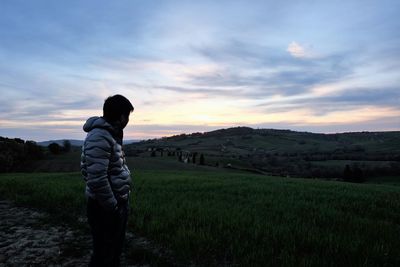Man standing on field against sky during sunset