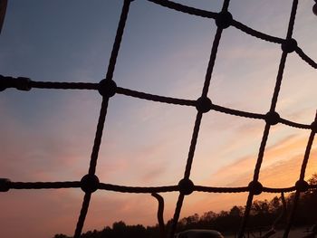 Low angle view of silhouette fence against sky during sunset