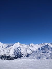 Scenic view of snowcapped mountains against clear blue sky