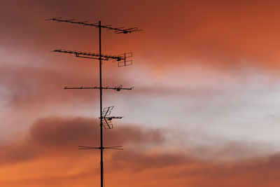 Low angle view of silhouette communications tower against dramatic sky