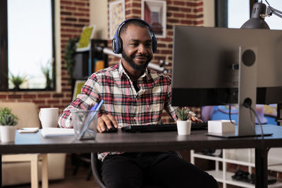 Portrait of young man using laptop while sitting on table