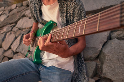 Midsection of man playing guitar