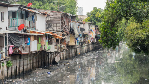 Houses by river amidst buildings in city