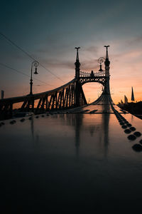 Silhouette of bridge over river during sunset