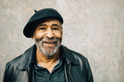 Portrait of smiling senior man against wall