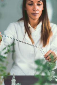 Young scientist pouring medicine in test tube from pipette at laboratory