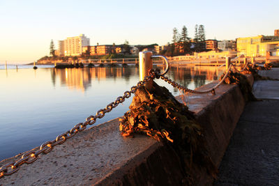 Chain on retaining wall at pier by sea against sky