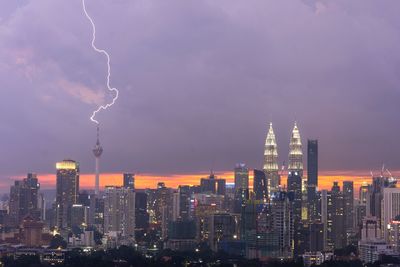 View of thunderstorm over cityscape at dusk