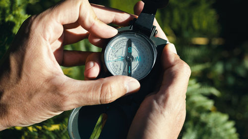 Hands of a boy opens the compass in the mountains to orient himself in the hike.