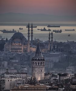 High angle view of galata tower and blue mosque by sea during sunset
