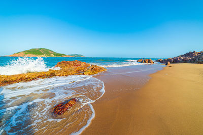 Scenic view of beach against clear blue sky